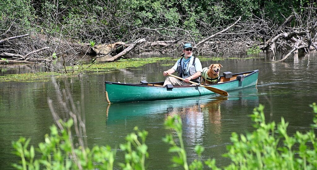 man in canoe with dog